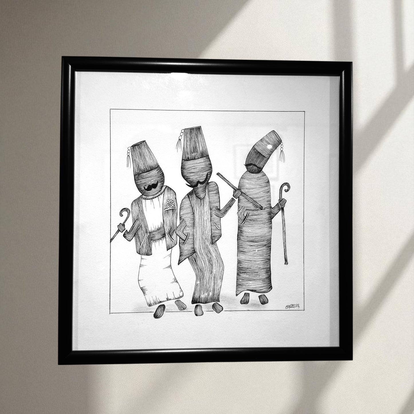 Framed black and white artwork of three figures with hats