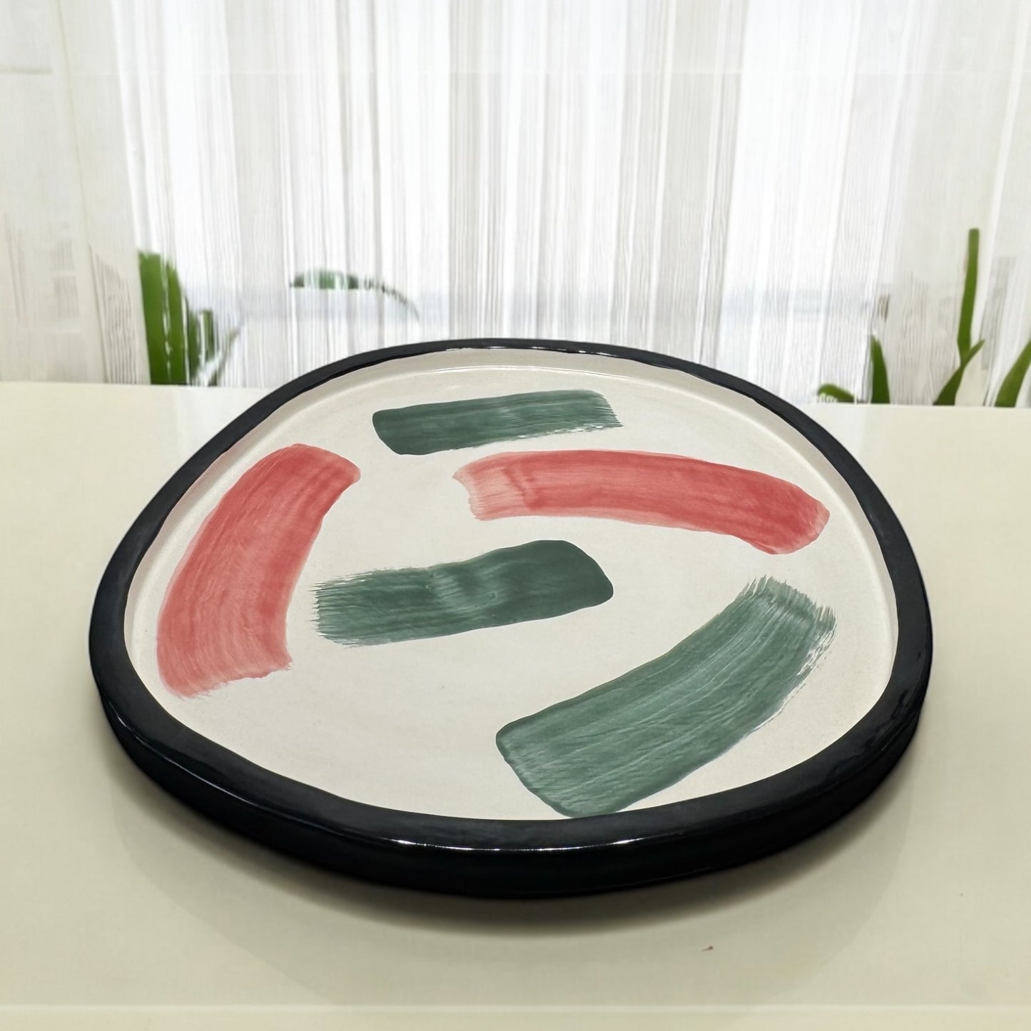 Round ceramic plate with black rim and colorful brush strokes