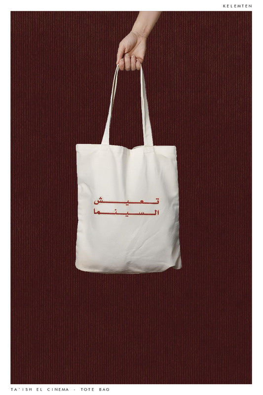 A white tote bag with a graphic print in the center "taiish el cinema"