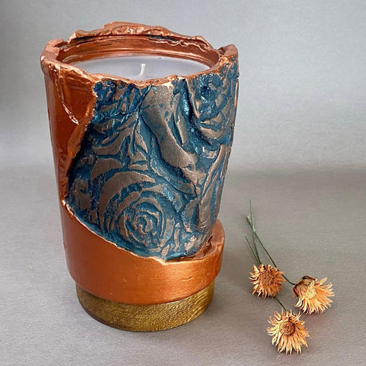 A large, circular candle predominantly in shades of blue and brown.